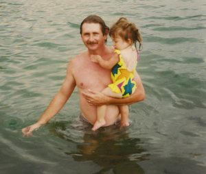 Dad carrying daughter in a river