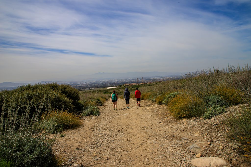 three people walking down a rocky trail