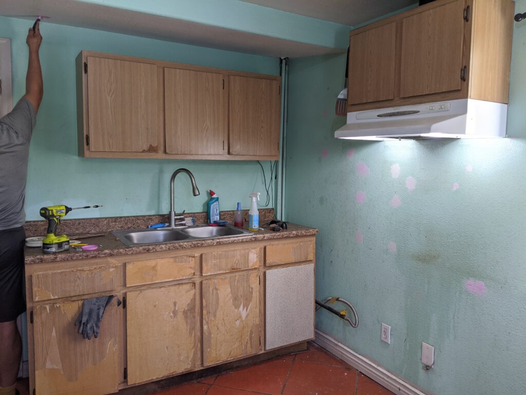 Old dirty brown kitchen cabinets in a kitchen being emptied for painting