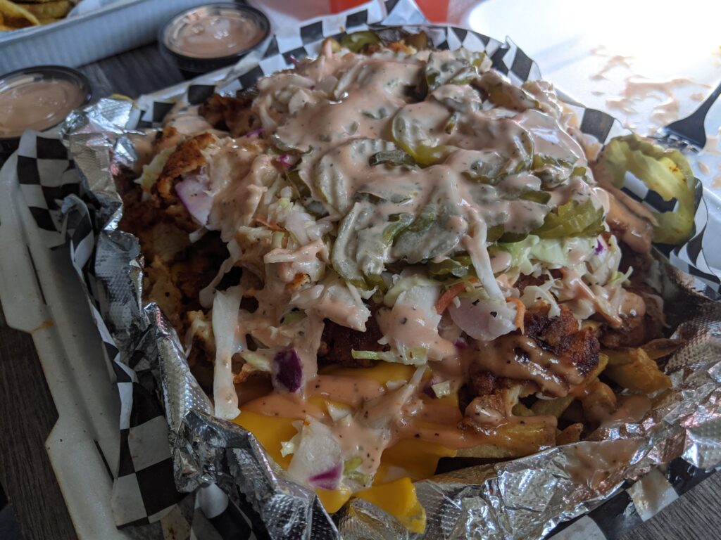 Fries topped with sauce, chicken, cheese, pickles and coleslaw